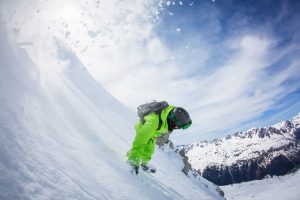 Snowboarder riding down the mountain in the powder